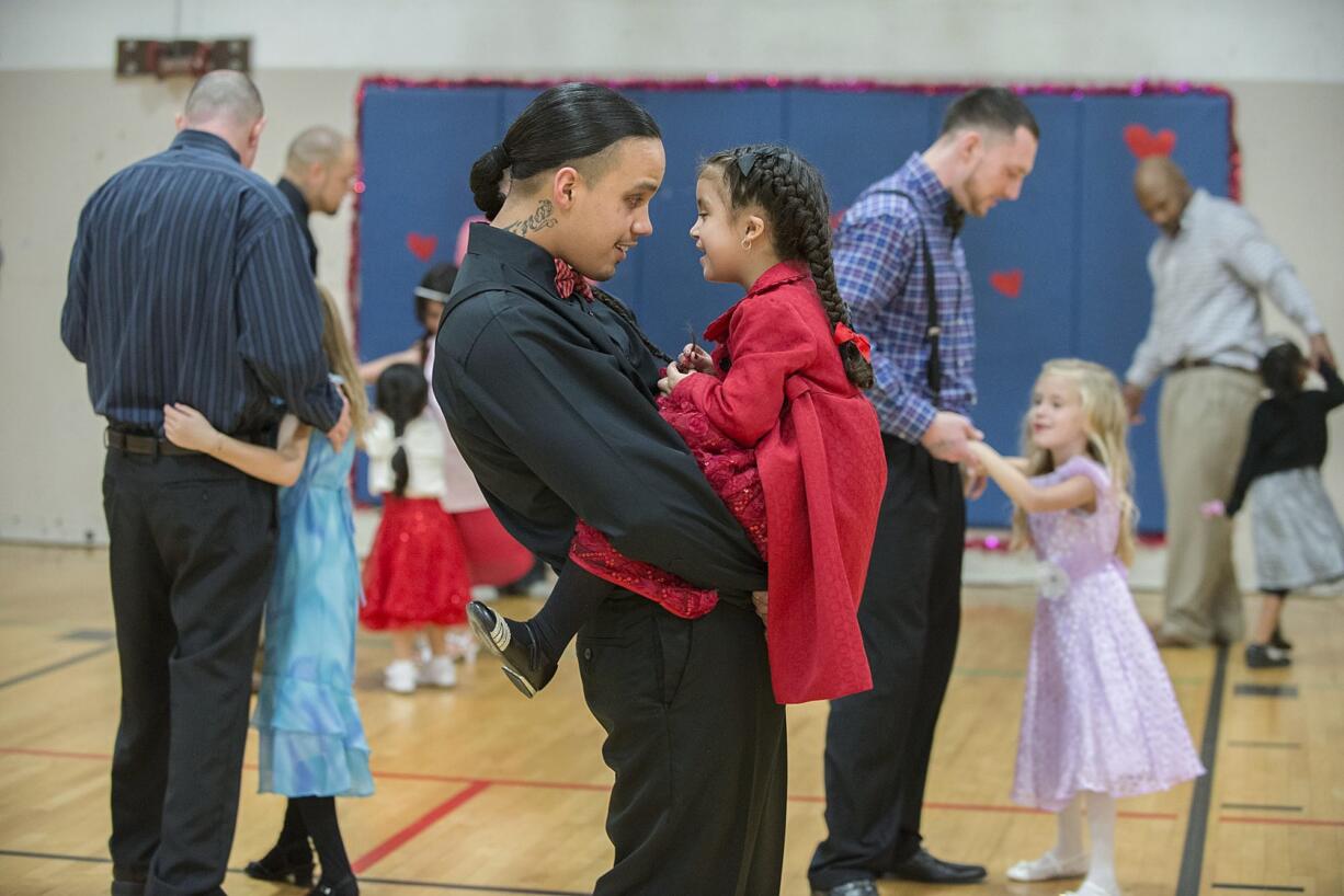 Kirk Hernandez Jr., center, an inmate at Larch Corrections Center, takes a turn around the dance floor during a slow song with his daughter, Eternity, 5, on Saturday during the prison&#039;s father-daughter dance.