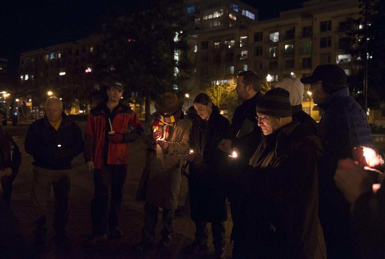 Adam Kravitz, right, founder of Outsiders Inn, leads a late December candlelight vigil as members of the community remember homeless people who died in the past year.