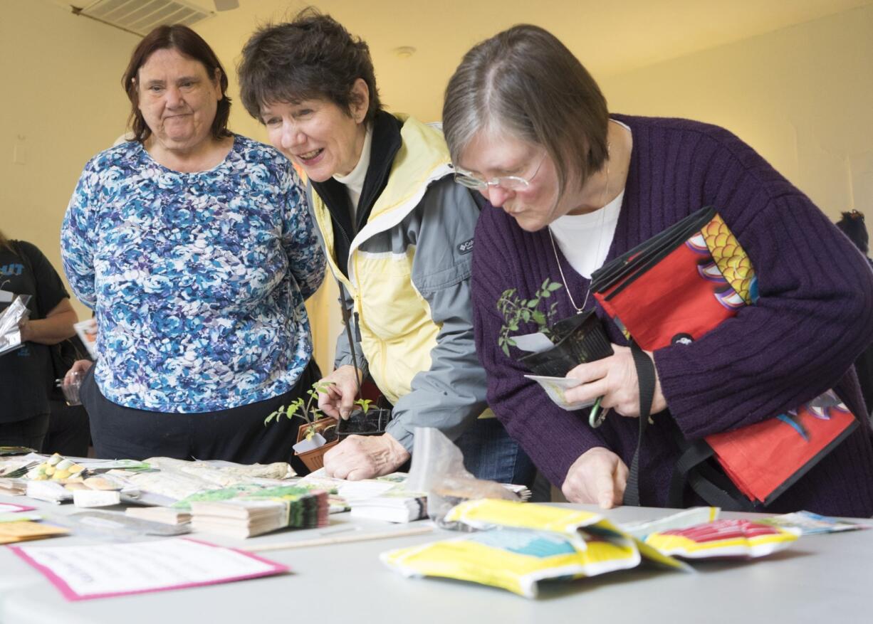 Judy McConathy of Vancouver, from left, Marie Coffey of La Center and Darin Woodman of Vancouver look over the selection at the Great Clark County Seed Swap on Saturday afternoon at the La Center Grange. The second annual event offered a wide variety of nonhybrid seeds.