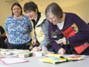 Judy McConathy of Vancouver, from left, Marie Coffey of La Center and Darin Woodman of Vancouver look over the selection at the Great Clark County Seed Swap on Saturday afternoon at the La Center Grange. The second annual event offered a wide variety of nonhybrid seeds.