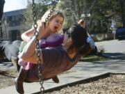 Jocelyn Leonard-Ulrich, 4, swings with her mother, Melissa Ulrich, on Monday at Esther Short Park in downtown Vancouver. Jocelyn has been learning how to use a swing set, her mother said.