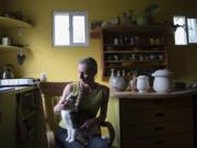 Potter Careen Stoll pets her cat, Butoh, while surrounded by some of her work at her studio in Battle Ground. Taking breaks is important for Stoll to stay healthy as she is basically a one-woman factory.