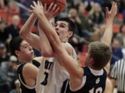 King's Way Christian's Kienan Walter, center, shoots against Cascade Christian defenders during playoff game at Battle Ground High School.