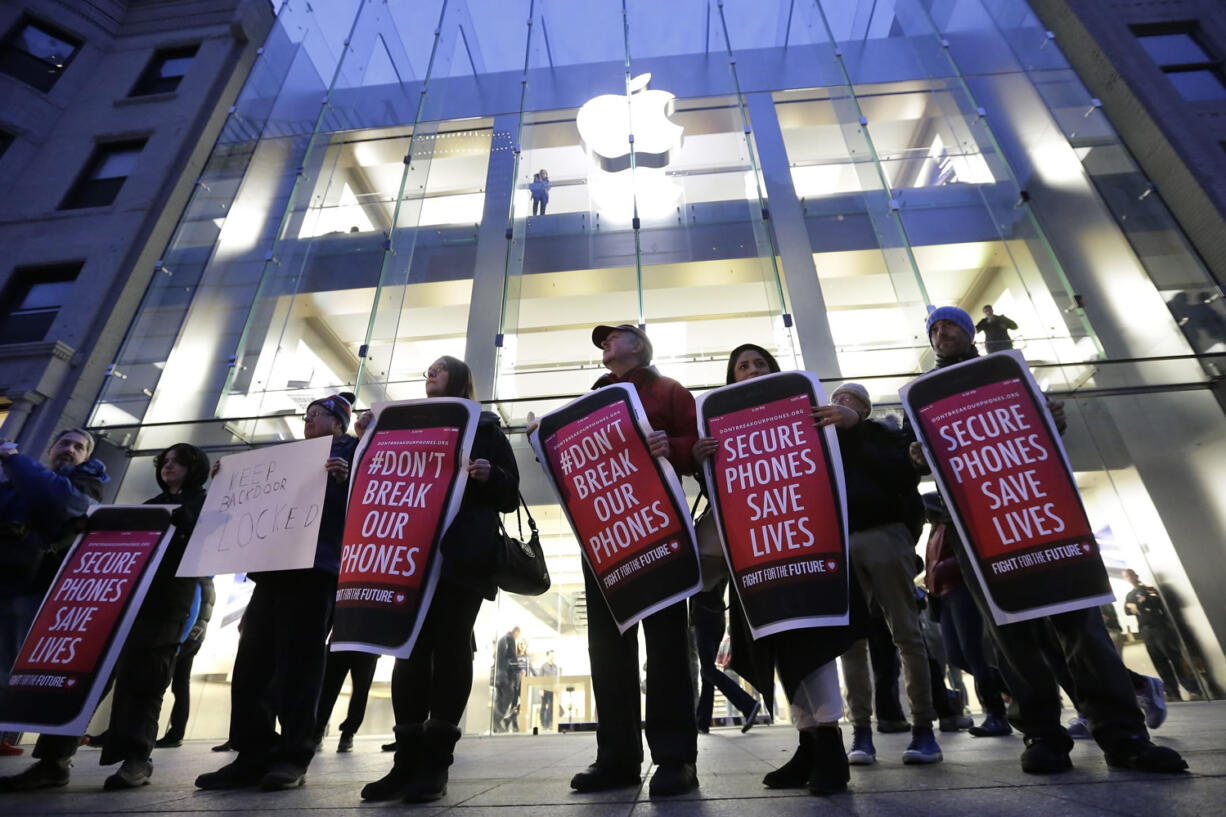 Protesters carry placards outside an Apple store Tuesday in Boston to protest the FBI obtaining a court order that requires Apple to make it easier to unlock an encrypted iPhone used by a gunman in December&#039;s shooting in San Bernardino, Calif.