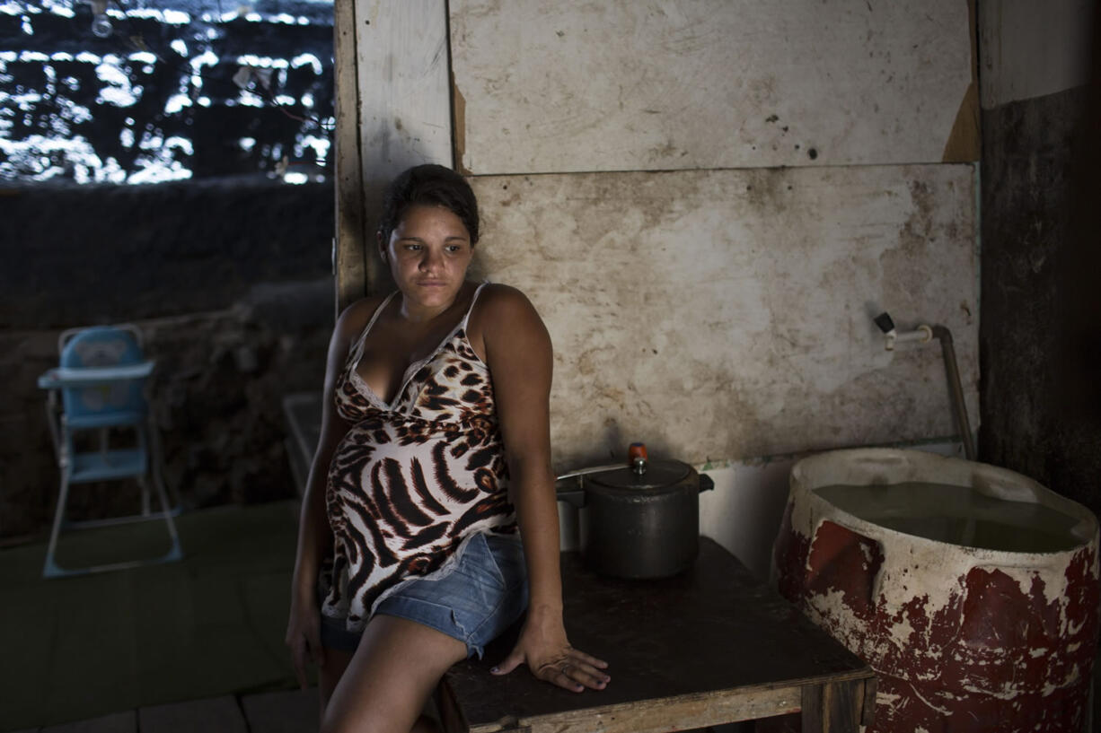 Leydiane da Silva, who is eight months pregnant, rests next to a water storage container, a potential mosquito breeding site, Monday inside her home in a slum in Recife, Brazil.