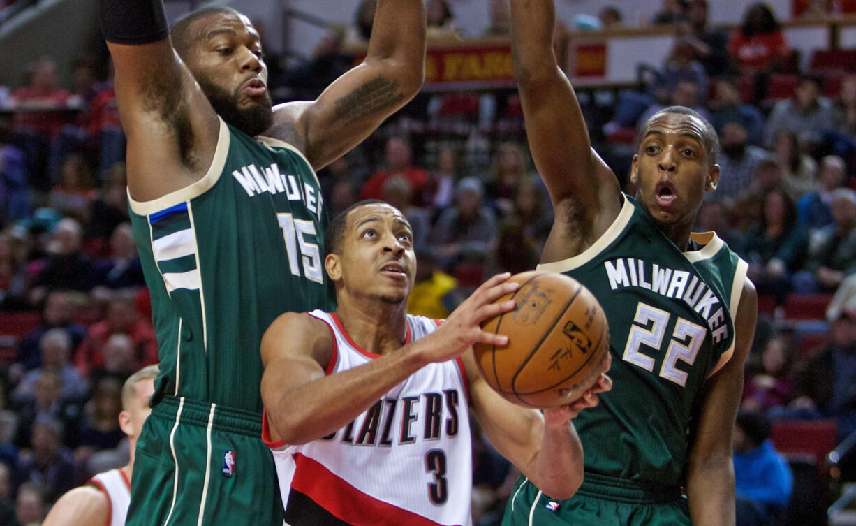 Portland Trail Blazers guard C.J. McCollum, center, shoots between Milwaukee Bucks center Greg Monroe, left, and guard Khris Middleton during the second half of an NBA basketball game in Portland, Ore., Tuesday, Feb. 2, 2016. The Trail Blazers won 107-95.