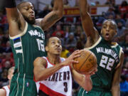 Portland Trail Blazers guard C.J. McCollum, center, shoots between Milwaukee Bucks center Greg Monroe, left, and guard Khris Middleton during the second half of an NBA basketball game in Portland, Ore., Tuesday, Feb. 2, 2016. The Trail Blazers won 107-95.