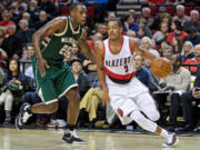 Portland Trail Blazers guard C.J. McCollum, right, dribbles past Milwaukee Bucks guard Khris Middleton during the second half of an NBA basketball game in Portland, Ore., Tuesday, Feb. 2, 2016. The Trail Blazers won 107-95.