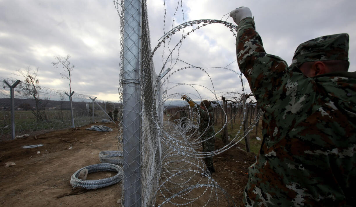 Macedonian Army soldiers attach a razor wire to a fence on Feb. 8 on the border line with Greece, near the southern Macedonian town of Gevgelija, Six nations from Central and Eastern Europe meet Monday in Prague to discuss plans for a new &quot;line of defense&quot; for Europe that involves a double fence along Greece&#039;s northern border.