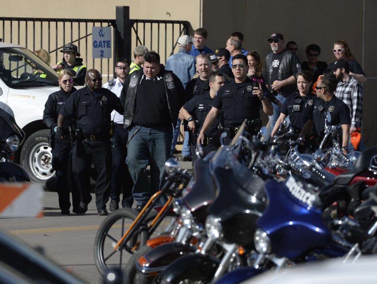 Denver Police escort a man in handcuffs away from the National Western Complex on Saturday in Denver. Denver police say multiple people were injured in a deadly stabbing and shooting at The Colorado Motorcycle Expo.