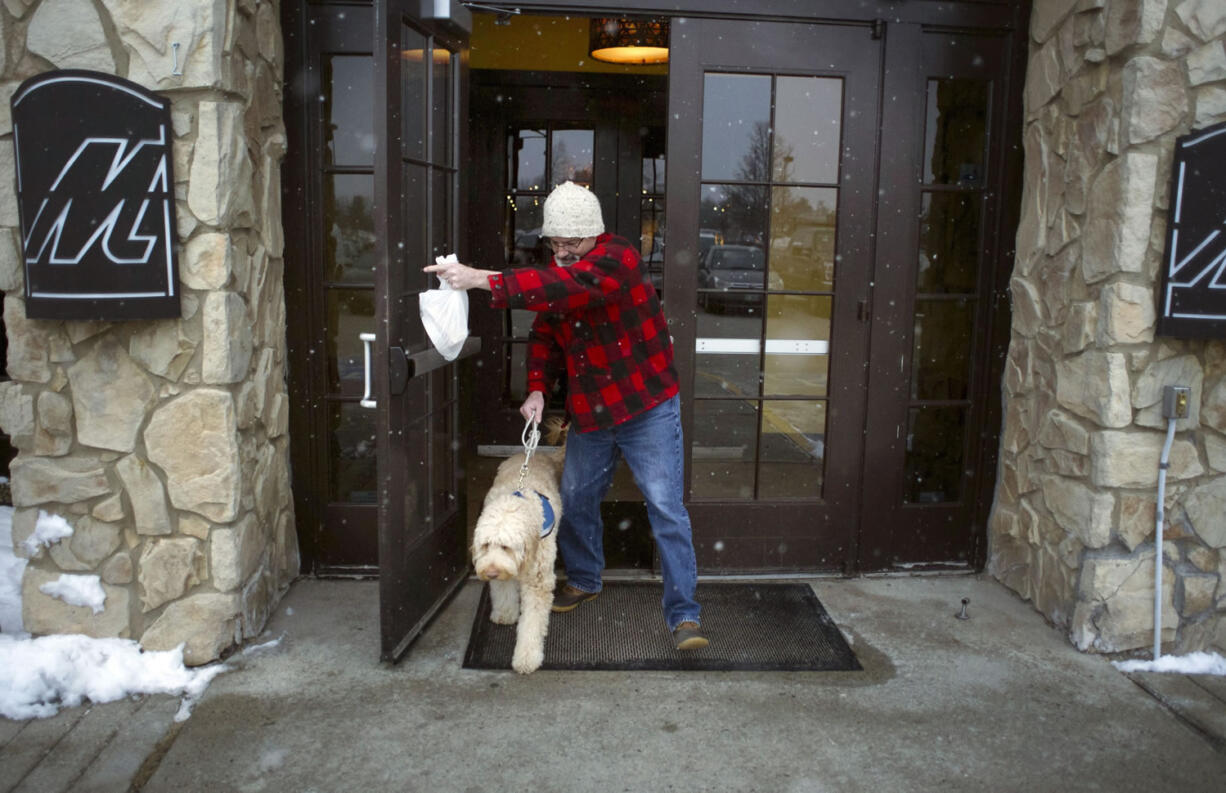 In this Monday, Feb. 8, 2016 photo, Sean McDonough leaves Macaroni Grill in South Portland, Maine, after eating lunch with his service dog Bruno at his side. McDonough suffered brain injuries in a car crash in 2008 and depends on Bruno to keep him calm in public settings. When McDonough is stressed, Bruno will lean against him. ?Businesses are so fed up with the fakes that those of us with legitimate service dogs are being scrutinized and discriminated against,? McDonough said.