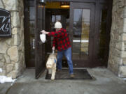 In this Monday, Feb. 8, 2016 photo, Sean McDonough leaves Macaroni Grill in South Portland, Maine, after eating lunch with his service dog Bruno at his side. McDonough suffered brain injuries in a car crash in 2008 and depends on Bruno to keep him calm in public settings. When McDonough is stressed, Bruno will lean against him. ?Businesses are so fed up with the fakes that those of us with legitimate service dogs are being scrutinized and discriminated against,? McDonough said.