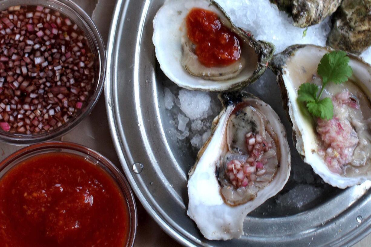 This Nov. 30, 2015 photo shows raw oysters with cocktail sauces mignonette sauce, top, and cocktail sauce, in Concord, NH. One of Valentine&#039;s Day&#039;s enduring customs is to launch the annual Feast of Love with a dozen raw oysters on the half shell washed down with a chilled bottle of bubbly. The briny bivalves have long enjoyed a reputation as an aphrodisiac.