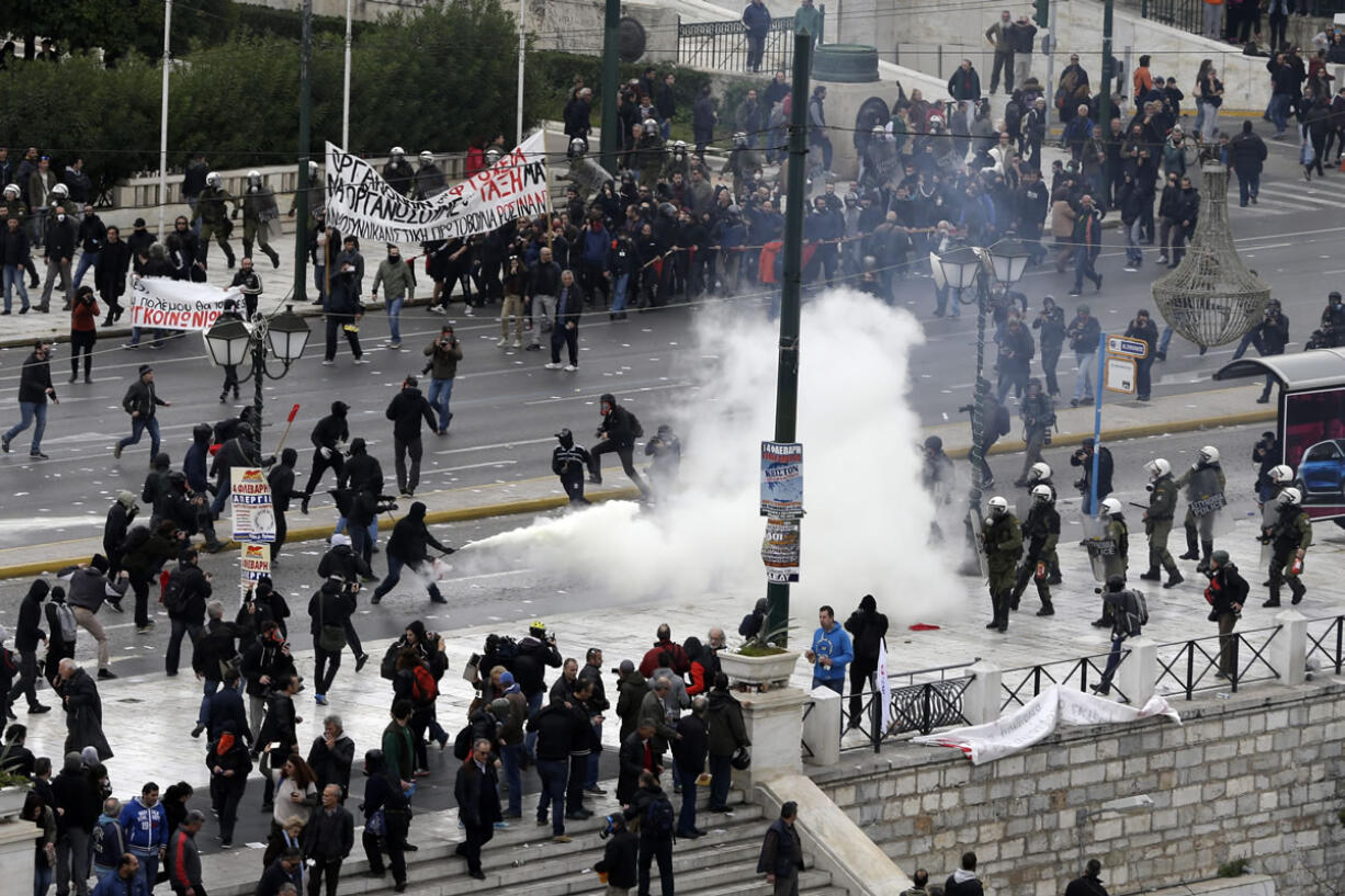 A protester uses a fire extinguisher against riot policemen during a 24-hour nationwide general strike in Athens, Thursday, Feb. 4, 2016. Clashes have broken out between Greek police and youths throwing fire bombs and stones, as tens of thousands of people march through central Athens to protest planned pension reforms.