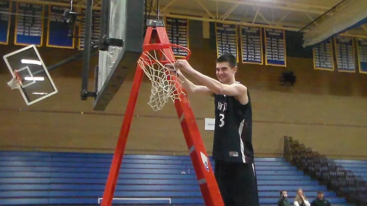 King's Way Christian's Kienan Walter cuts down the net after the Knights' district championship win (Tim Martinez/The Columbian)