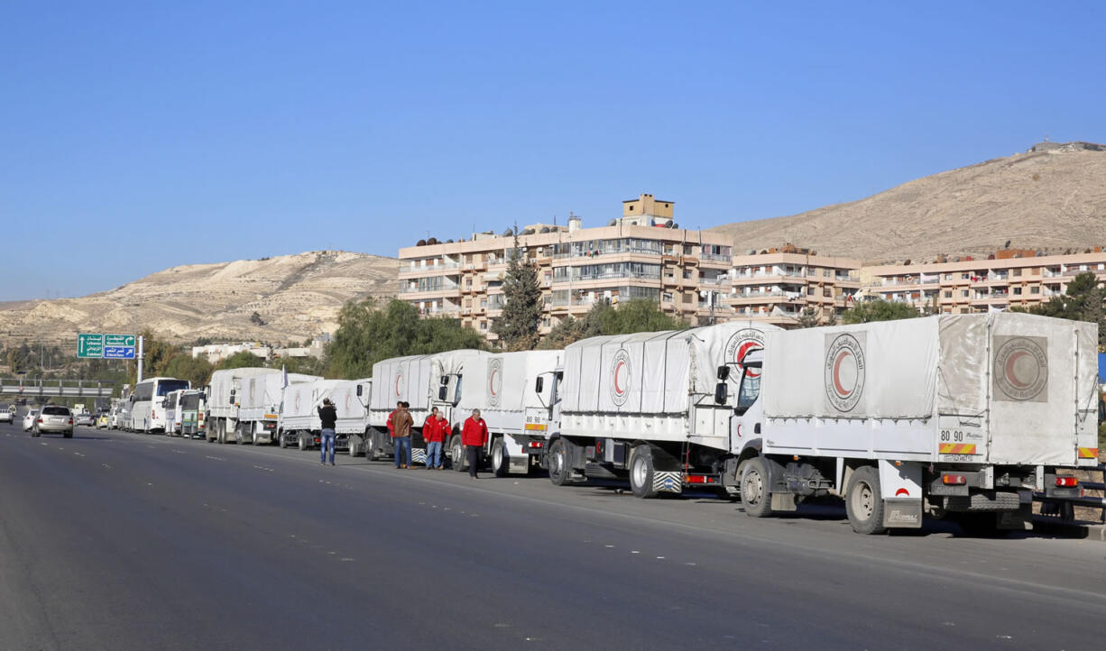 A convoy of humanitarian aid waits in front of the United Nations Relief and Works Agency (UNRWA) offices before making their way into the government besieged rebel-held towns of Madaya, al-Zabadani and al-Moadhamiya in the Damascus countryside, as part of a U.N.-sponsored aid operation, in Damascus, Syria, Wednesday,  Feb. 17,  2016. A similar convoy is headed to the villages of Foua and Kfraya in the northern Idlib province, which are besieged by rebels. The convoys represent the third humanitarian aid delivery to the besieged communities after two similar efforts last month.