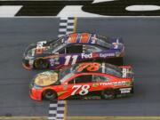 Denny Hamlin (11) beats out Martin Truex Jr. (78) at the finish line to win the NASCAR Daytona 500 auto race at Daytona International Speedway, Sunday, Feb. 21, 2016, in Daytona Beach, Fla.