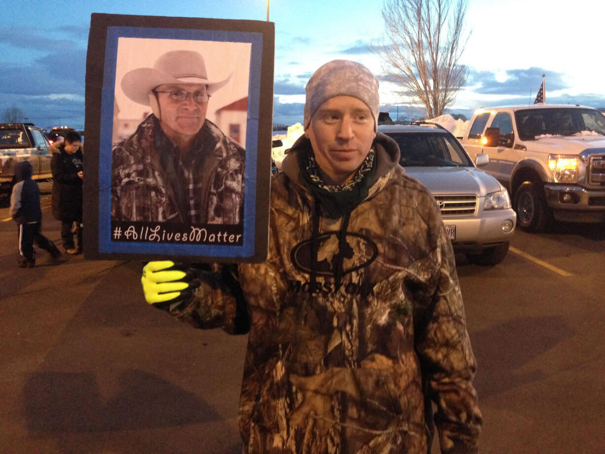 Tony Atencio of Burns, Oregon, holds a photo of rancher Robert ``LaVoy'' Finicum at a rally against Finnicum's slaying by law enforcement officers, and the presence of numerous heavily armed law enforcement officers at the standoff, Saturday, Jan. 30, 2016, in Burns, Oregon. Four people occupying the wildlife refuge held their position Sunday. They have demanded that they be allowed to leave without being arrested.   (AP Photo/Nicholas K.