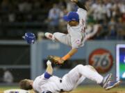 New York Mets shortstop Ruben Tejada, goes over the top of Los Angeles Dodgers' Chase Utley who broke up a double play during the seventh inning in Game 2 of baseball's National League Division Series, in Los Angeles on Oct. 10, 2015. Major League Baseball and the players' association have banned rolling block slides to break up potential double plays, hoping to prevent a repeat of the takeout by Dodgers' Chase Utley that broke a leg of Mets Ruben Tejada in last years playoffs. Under the rules change announced Thursday, Feb. 25, 2016, a runner must make a "bona fide slide," defined as making contact with the ground ahead of the base, being in position to reach the base with a hand or foot and to remain on it, and sliding within reach of the base without changing his path to initiate contact with a fielder.