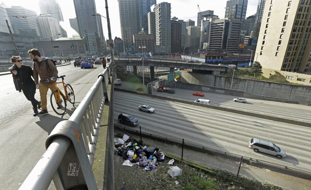 Pedestrians walk above signs of a homeless encampment near a bridge over the Interstate 5 freeway in downtown Seattle on Feb. 9. Even as homelessness declined slightly nationwide in 2015, it increased in urban areas, including Seattle, New York and Los Angeles. (AP Photo/Ted S.