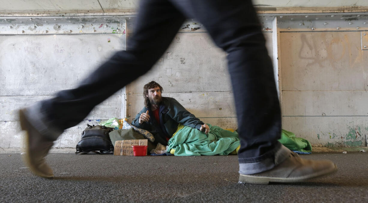 Harold McDuffie II, who says he has been homeless for three years, watches pedestrians pass by as he lies in a sleeping bag on a bridge leading to the ferry dock in downtown Seattle on Feb. 9. Seattle has the third-highest number of homeless people in the U.S. (AP Photo/Ted S.