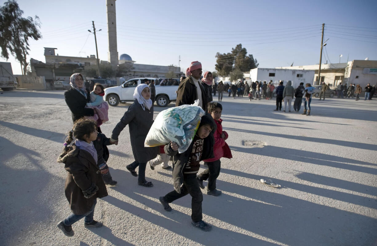 Syrians walk toward the Turkish border Friday at the Bab al-Salam border gate, Syria. Turkish officials say thousands of Syrians have massed on the Syrian side of the border seeking refuge in Turkey. Officials at the government's crisis management agency said Friday it was not clear when Turkey would open the border to allow the group in and start processing them. The refugees, who fled bombing in Aleppo, were waiting at the Bab al-Salam crossing, opposite the Turkish province of Kilis.