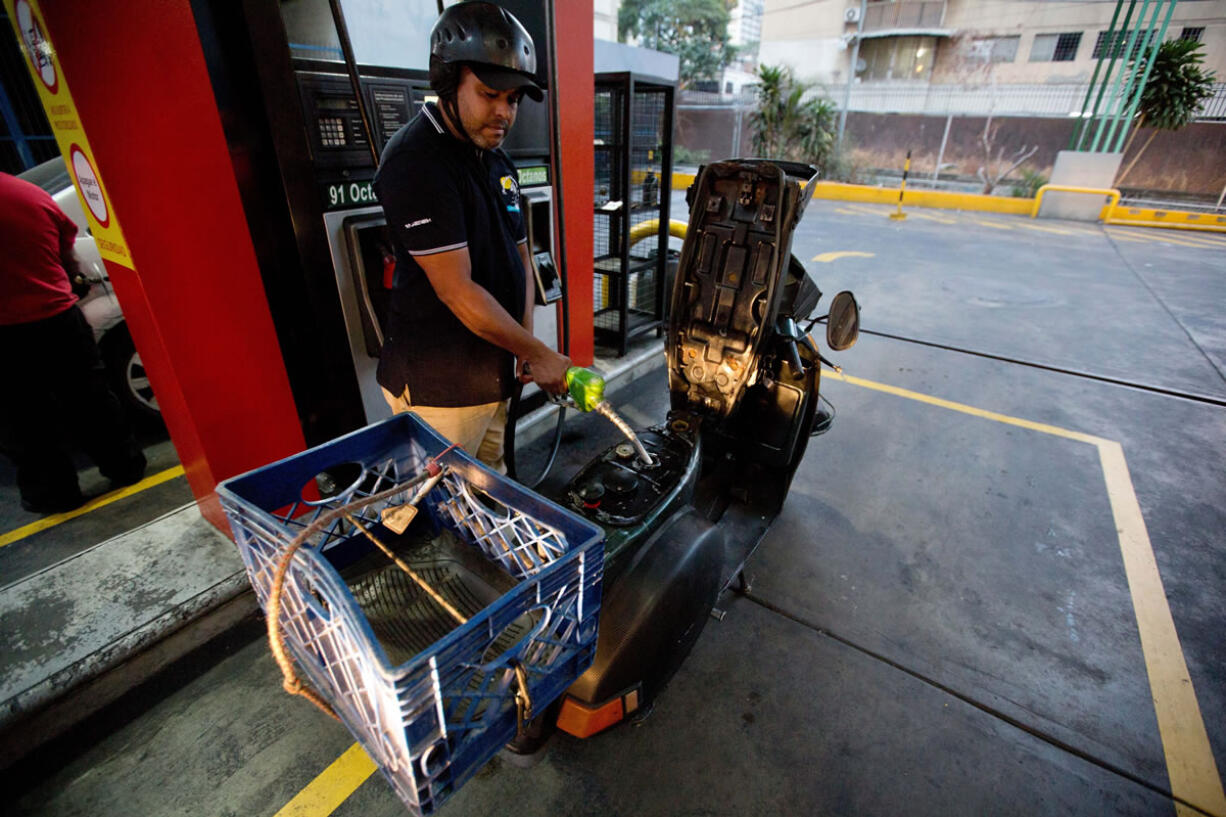 A man fills his scooter with fuel at a gas station in Caracas, Venezuela, Wednesday, Feb. 17, 2016. Venezuela's government is raising gasoline prices sixtyfold — the first increase of any kind in more than 17 years as the country struggles with an economic collapse. Yet drivers will still be able to fill their tanks for pennies.