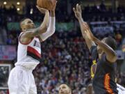 Portland Trail Blazers guard Damian Lillard, left, shoots over Golden State Warriors forward Harrison Barnes, right, during the second half of an NBA basketball game in Portland, Ore., Friday, Feb. 19, 2016.