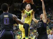 Oregon's Dillon Brooks, center, drives to the basket between Washington's Marquese Chriss, left, and Dominic Green, right, during the first half of an NCAA college basketball game Sunday, Feb. 28, 2016 in Eugene, Ore.