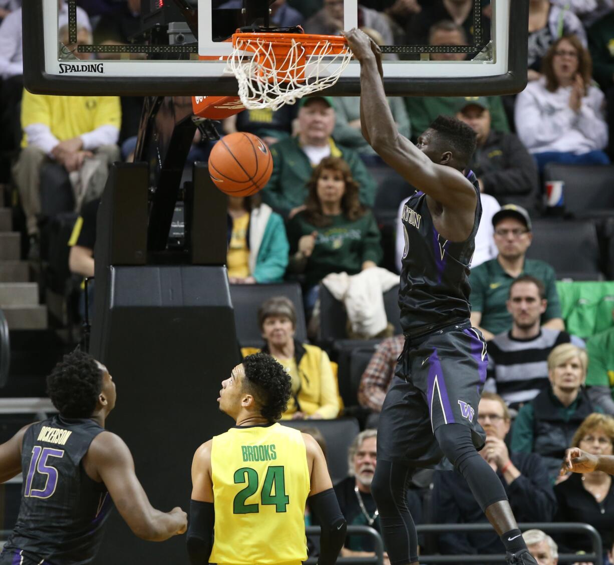 Washington's Malik Dime, top, dunks over teammate Noah Dickerson, left, and Oregon's Dillon Brooks during the first half of an NCAA college basketball game, Sunday, Feb. 28, 2016 in Eugene, Ore.