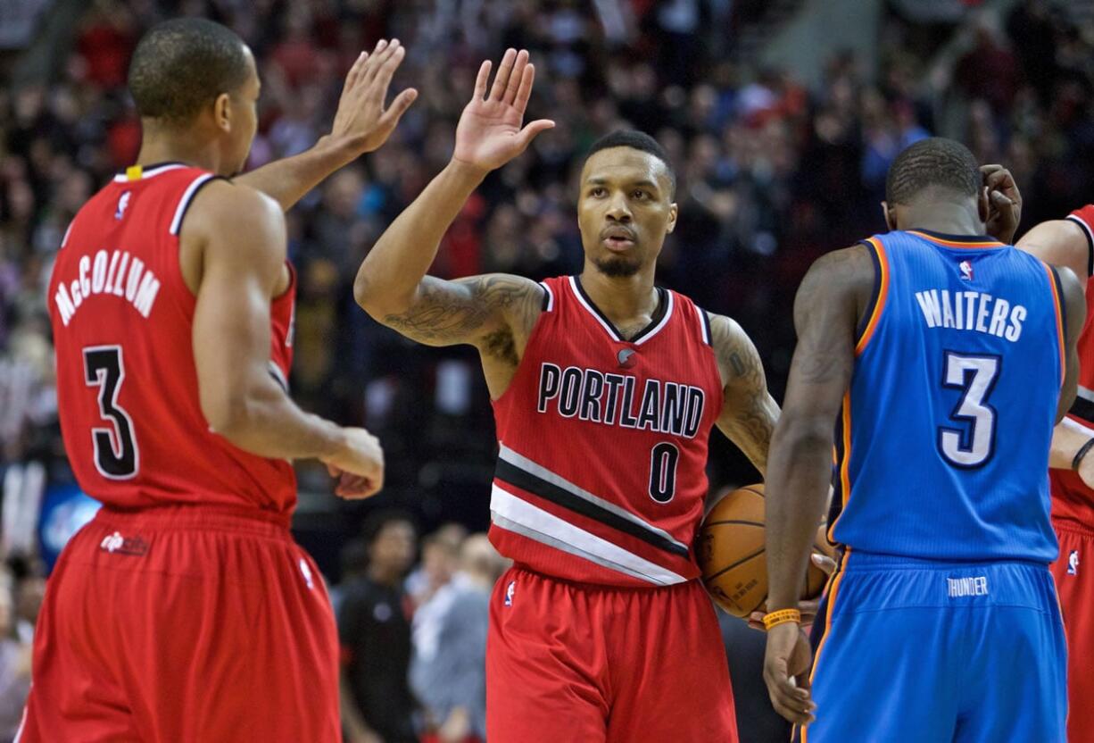 Portland Trail Blazers guard Damian Lillard high-fives guard C.J. McCollum, left, during the second half of an NBA basketball game against the Oklahoma City Thunder in Portland, Ore., Sunday, Jan. 10, 2016. The Trail Blazers won 115-110.