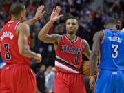 Portland Trail Blazers guard Damian Lillard high-fives guard C.J. McCollum, left, during the second half of an NBA basketball game against the Oklahoma City Thunder in Portland, Ore., Sunday, Jan. 10, 2016. The Trail Blazers won 115-110.