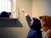 Dressed up for the occasion, Wilhem Arthur, left, and Andrew Telepak coax Oreo into playing with a cat toy during the grand opening of Le Cat Cafe on March 6, 2016 in Philadelphia, Pa. The cat cafe will be operated by Green Street Rescue&#039;s Kathy Jordan, permitting the cats and potential adopters to hang out together in a living room environment.