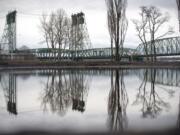 The waterfront and the Interstate 5 Bridge is seen reflected in a puddle left by December rain in Vancouver.