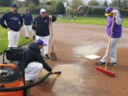 Coaches from the Skyview and Columbia River baseball teams try to get the Columbia River High School baseball field dry before a game last season. Teams have faced worst weather problems this year.