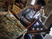 Next to the camouflage uniform of his late son, Army National Guard Spc. Benjamin Pleitez, Salvador Pleitez looks at the flag that draped his casket after he was killed in Mazar-e-Sharif, Afghanistan in 2012.