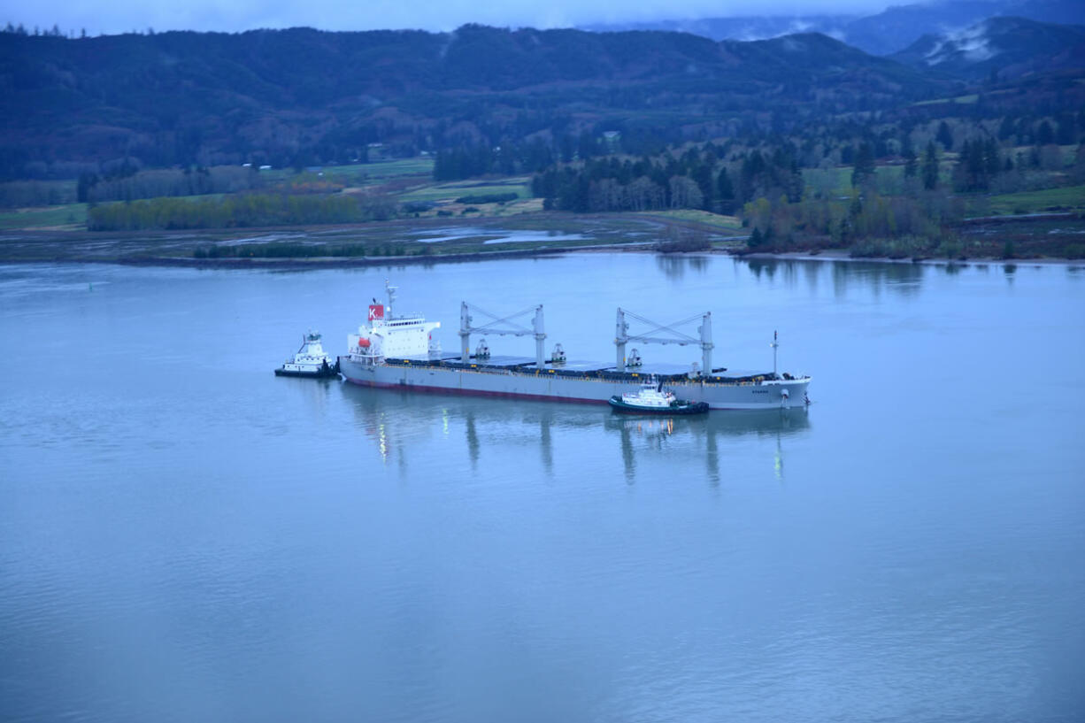 Two tugs assist the motor vessel Sparna, a 623-foot Panamanian-flagged bulk carrier with a load of grain, after the vessel reportedly ran aground in the Columbia River near Cathlamet, Wash., March 21, 2016. A salvage plan must be approved by the Coast Guard before the vessel can be refloated. (U.S.