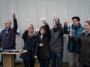 John McKibbin's family and the Rev. Fitz Neal, left, hold up candles in remembrance of McKibbin's life at a vigil Saturday evening at Pearson Field in Vancouver.