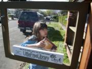 Zoe Chan, 7, adds a donated book to the Clark Avenue Little Free Library. Creating the little library was Zoe&#039;s idea.