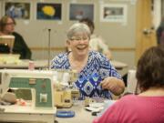 Janice Tope of Vancouver, center, shares a laugh with friend Phyllis McIntosh while sewing at Three Creeks Community Library.