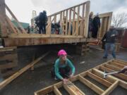 Evergreen High School sophomore Hailey Crater, 15, center, uses her math skills to measure a framed-out exterior wall on a Habitat for Humanity home students are building in their Geometry in Construction class.