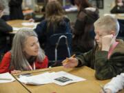 Caroline King, left, chief policy officer for Washington STEM, chats with sixth-grader Hayden Kahler, 11, about calculating the ratios of caffeine to sugar in coffee drinks during his math class Wednesday at Frontier Middle School.