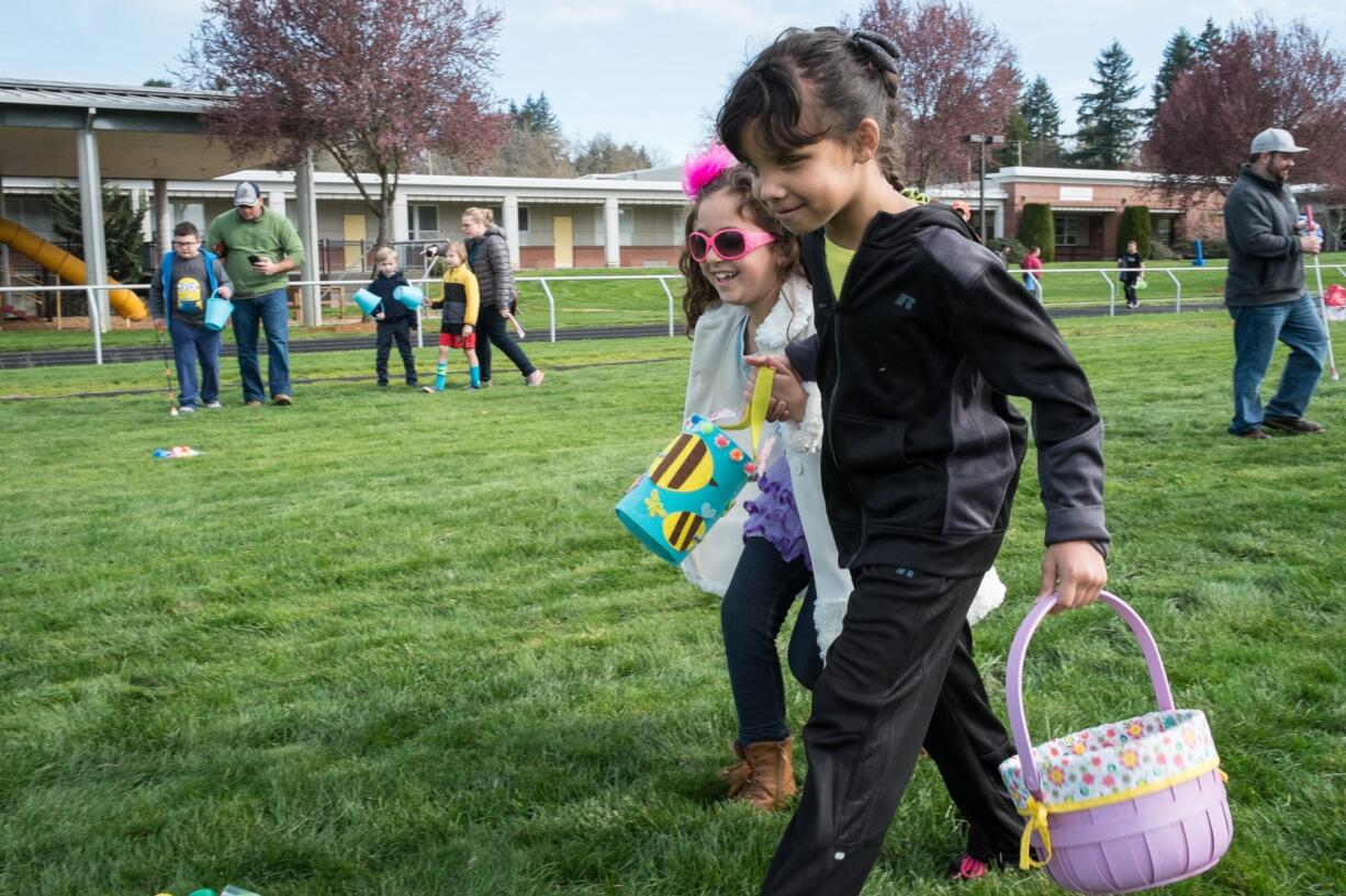 Angel Miller-Boyko, left in glasses, and Jasmine Eiland, both 7, search for Easter eggs at the Beeping Easter Egg Hunt for the Blind on Saturday morning.