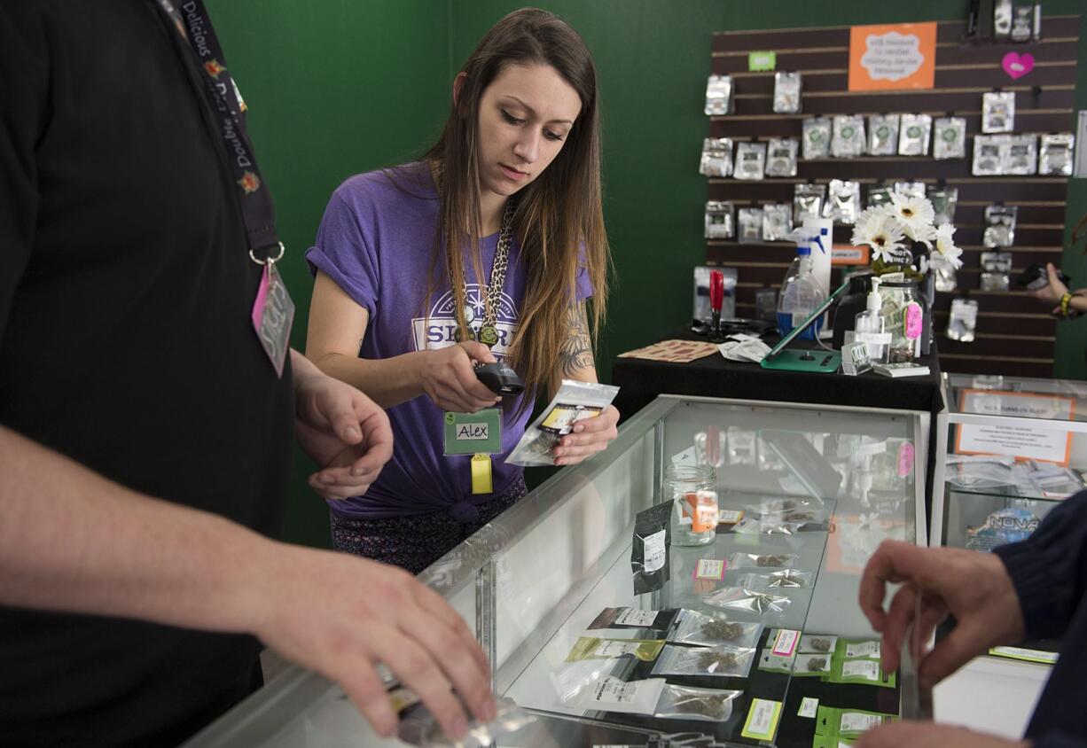 Assistant manager Alex McIntosh helps a customer while working behind the counter at Sticky&#039;s Pot Shop in Vancouver last week.