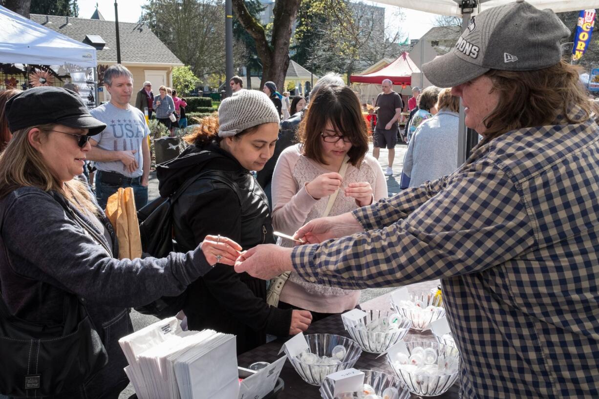 Vicki Allenback, right, owner of Skamokawa Farmstead Creamery, hands out free samples of goat cheese Saturday on opening day at the Vancouver Farmers Market.