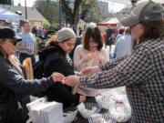 Vicki Allenback, right, owner of Skamokawa Farmstead Creamery, hands out free samples of goat cheese Saturday on opening day at the Vancouver Farmers Market.