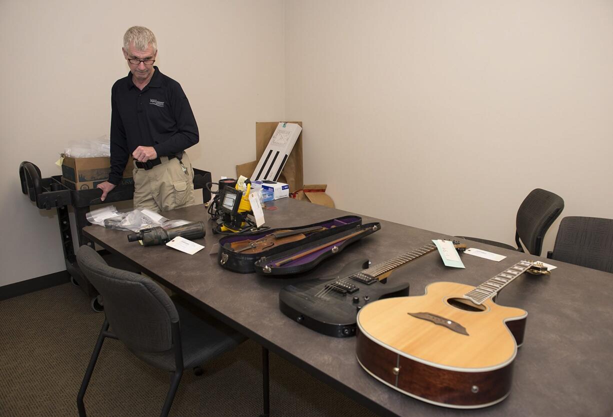 Evidence technician Kit Abernathy looks over items last month at the city of Vancouver&#039;s police evidence facility. Goods seized under asset forfeiture laws can be sold at auction.