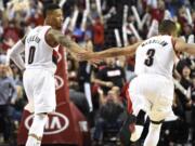 Portland’s Damian Lillard (0) celebrates with teammate C.J. McCollum (3) after McCollum made the go-ahead shot in the closing seconds of the fourth quarter Saturday. The Blazers won 108-105.