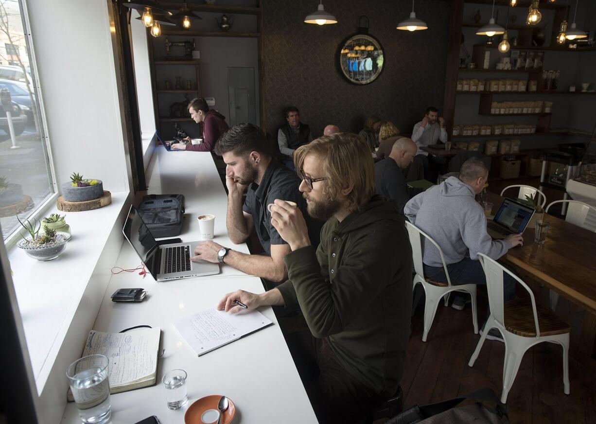 Tyler Eversaul, foreground, drinks his espresso with Christian Moothart on Monday afternoon at Compass Coffee in downtown Vancouver. The shop recently moved into 817 Washington St.