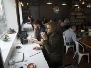 Tyler Eversaul, foreground, drinks his espresso with Christian Moothart on Monday afternoon at Compass Coffee in downtown Vancouver. The shop recently moved into 817 Washington St.